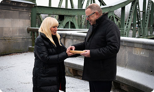Teaserbild von Stübgen und Spranger bei der Staffelstabübergabe an der Glienicker Brücke in Postdam